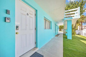 A corridor with teal walls, white doors, and a small window. - Fillmore Unit #1 | 2BR/1BA (Cape Canaveral)