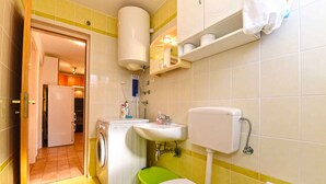 A compact bathroom with a toilet, sink, and washing machine.