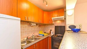 A compact kitchen with wooden cabinets, a gas stove, a built-in oven, and a microwave.