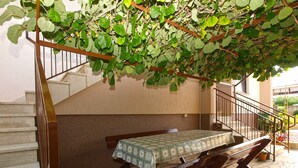 A covered outdoor seating area with a table and benches, a staircase, and potted plants. - Holiday apartment with air conditioning (Štinjan)