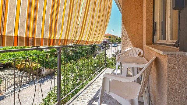 A balcony with a view of a street, a railing, and a table with chairs. - Studio with air conditioning (Pula)