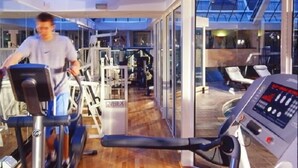 A gym with cardio equipment and weight machines, large windows, and a wooden floor. - The Aberdeen Dyce Hotel (Aberdeen)