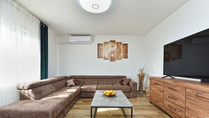 A modern living room with a sectional sofa, a coffee table, a wooden cabinet, and a flat-screen TV. - Holiday apartment with air conditioning (Rovinj)