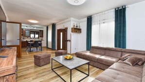 A modern living room with a brown leather sofa, a wooden dining table, and a kitchen in the background. - Holiday apartment with air conditioning (Rovinj)