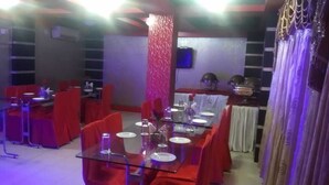 Un espace repas avec des tables disposées pour accueillir quatre personnes, des chaises rouges et une cloison en verre.