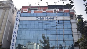 La façade extérieure de l’hôtel Orbit, avec sa grande surface vitrée et une enseigne indiquant son nom.