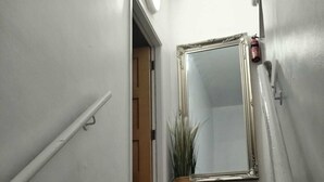 Un escalier avec une rampe, une plante en pot et un miroir accroché au mur.
