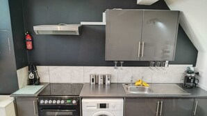 Une cuisine compacte équipée d’une cuisinière, d’un four, d’un lave-linge et d’un évier.