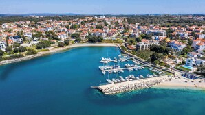 Vue aérienne d’une ville côtière avec un port de plaisance, des immeubles résidentiels et une plage.