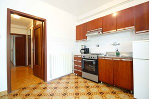 Een koelkast, een oven, een kookplaat, kookgerei, borden en bestek