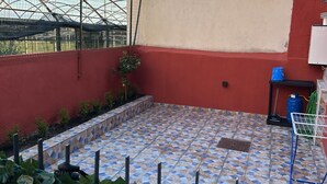 A rooftop patio with a tiled floor, a small garden area, and a metal structure. - 1 bedroom apartment in ercolano (Ercolano)