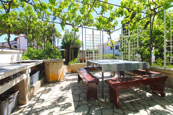 Une terrasse extérieure avec un sol en pierre, une table en bois et un banc.