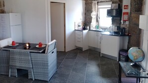 Eine kleine Küche mit Steinwand, ein Essbereich mit Korbmöbeln und ein Tisch mit Kerzen.