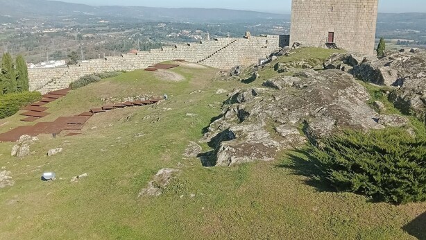 Ein Steinturm auf einem Hügel mit Blick auf ein darunter liegendes Tal.
