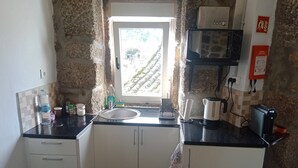 Eine kleine Küche mit Fenster, Mikrowelle, Wasserkocher und Kaffeemaschine.