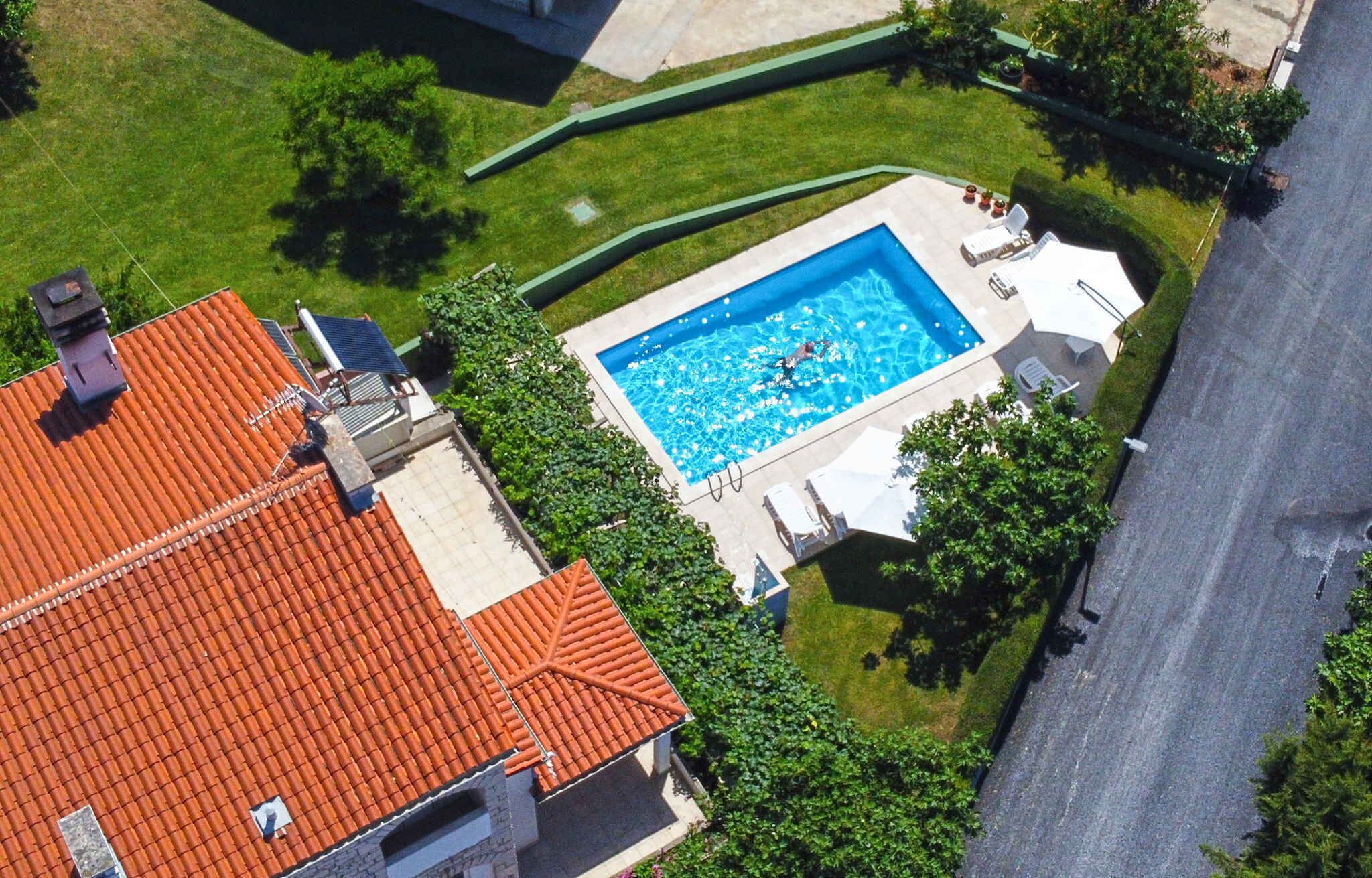 Una propiedad residencial con piscina, techo de tejas rojas y césped bien cuidado.