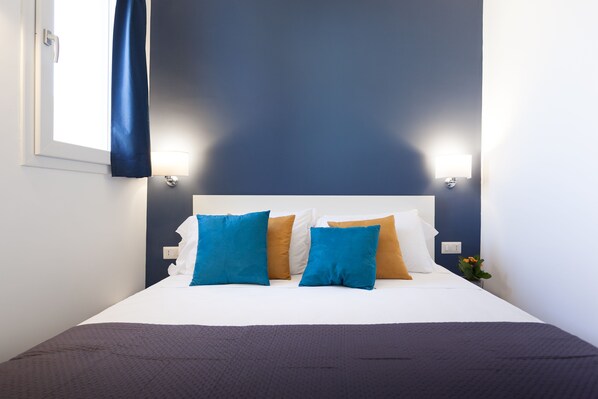 A neatly made bed with a white headboard, blue and brown pillows, and a dark blue blanket. - Terrasse Manuela Apartment 2 (Napoli)