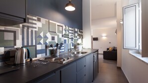 Een moderne keuken met een geometrisch patroon op de achterwand, een inbouw kookeiland met spoelbak en een hanglamp.