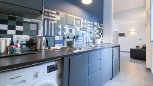 Een moderne keuken met een ingebouwde wasmachine, een koffiezetapparaat en een waterkoker op het aanrecht.