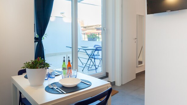 Een eetgedeelte met een tafel voor twee personen, een potplant en uitzicht op het balkon.