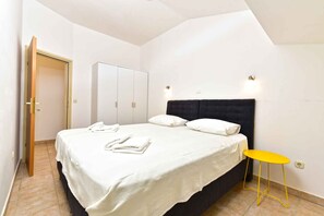 Ein Schlafzimmer mit Bett, Kleiderschrank, Nachttisch und Tür.