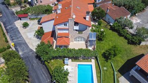 An aerial view of a residential area with a swimming pool, multiple houses with red-tiled roofs, and a street. - Holiday apartment with air conditioning (Medulin)