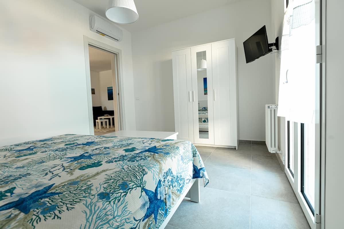 Ein Schlafzimmer mit Bett, Kleiderschrank, Fernseher und Fenster.