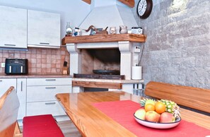 Enjoy cooking in this kitchen with a central stove, white cabinetry, and dining area.