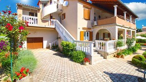 A two-story house with a balcony, a staircase, and a garden with potted plants. - Holiday apartment with air conditioning (Medulin)