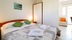 A hotel room with a bed, a nightstand, a painting, and a view of the outdoors. - Holiday apartment with air conditioning (Medulin)