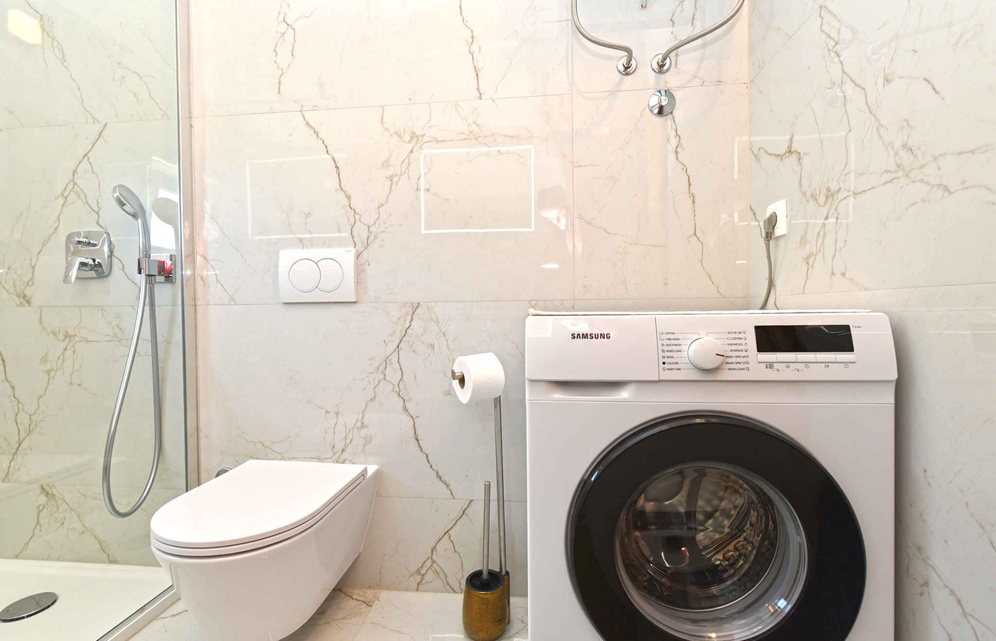 Une salle de bain équipée d’un lave-linge, de toilettes et d’une douche.