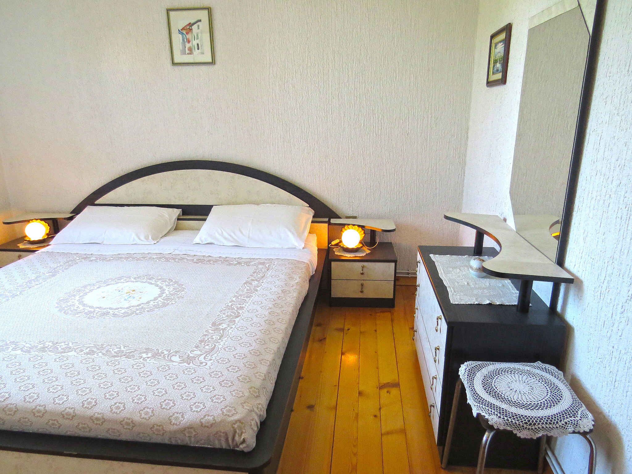 A bedroom with a bed, bedside tables, a mirror, and a small stool.
