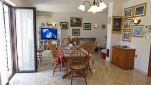 A dining area with a TV, dining table, chairs, and a cabinet. - Holiday apartment with air conditioning (Medulin)