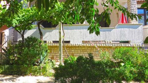 A building with a stone facade, multiple windows, and a balcony with a red umbrella. - Holiday apartment with air conditioning (Medulin)