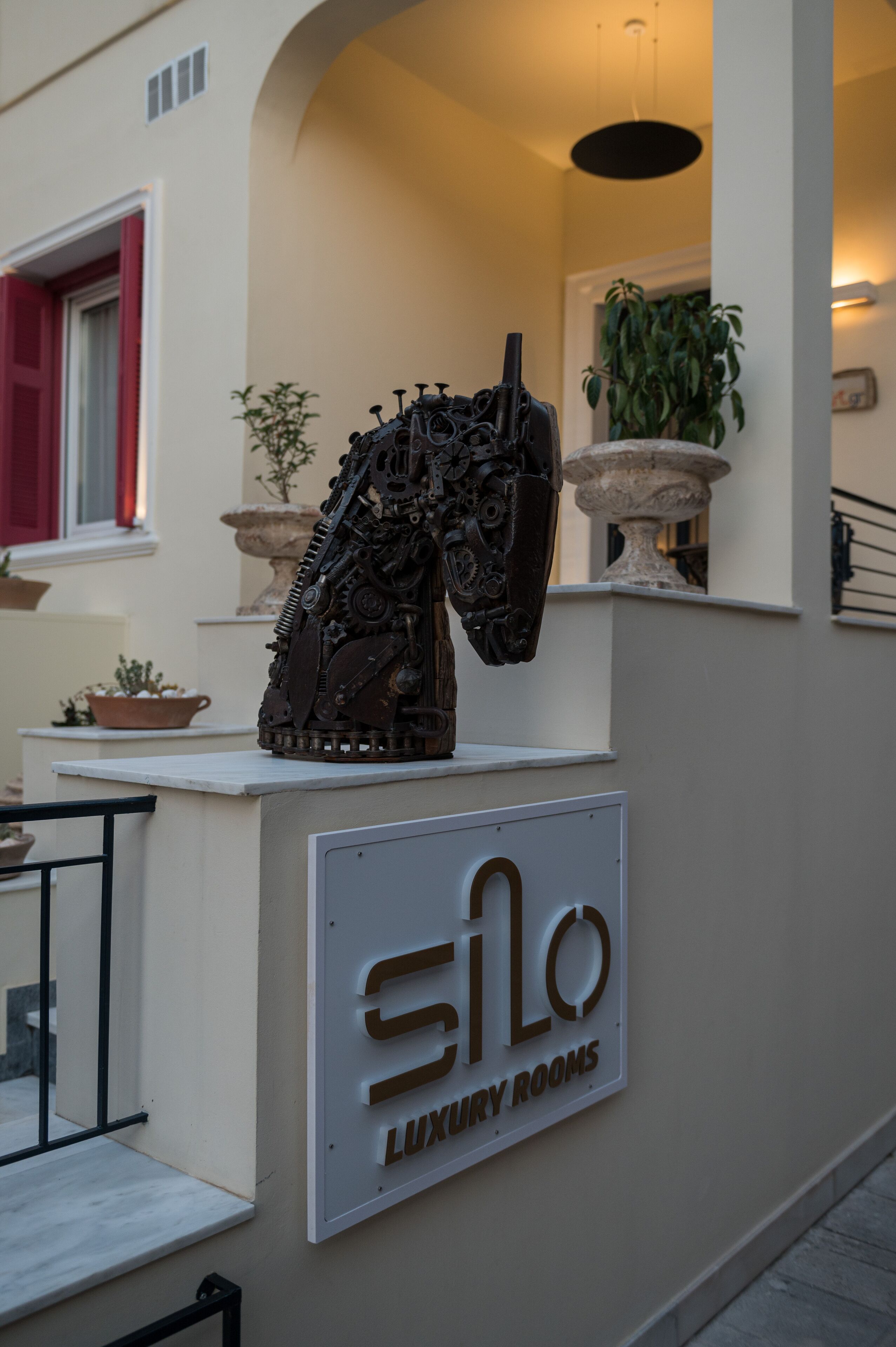 A sign for "SiLo Luxury Rooms" with a unique sculpture of a horse head in the foreground.