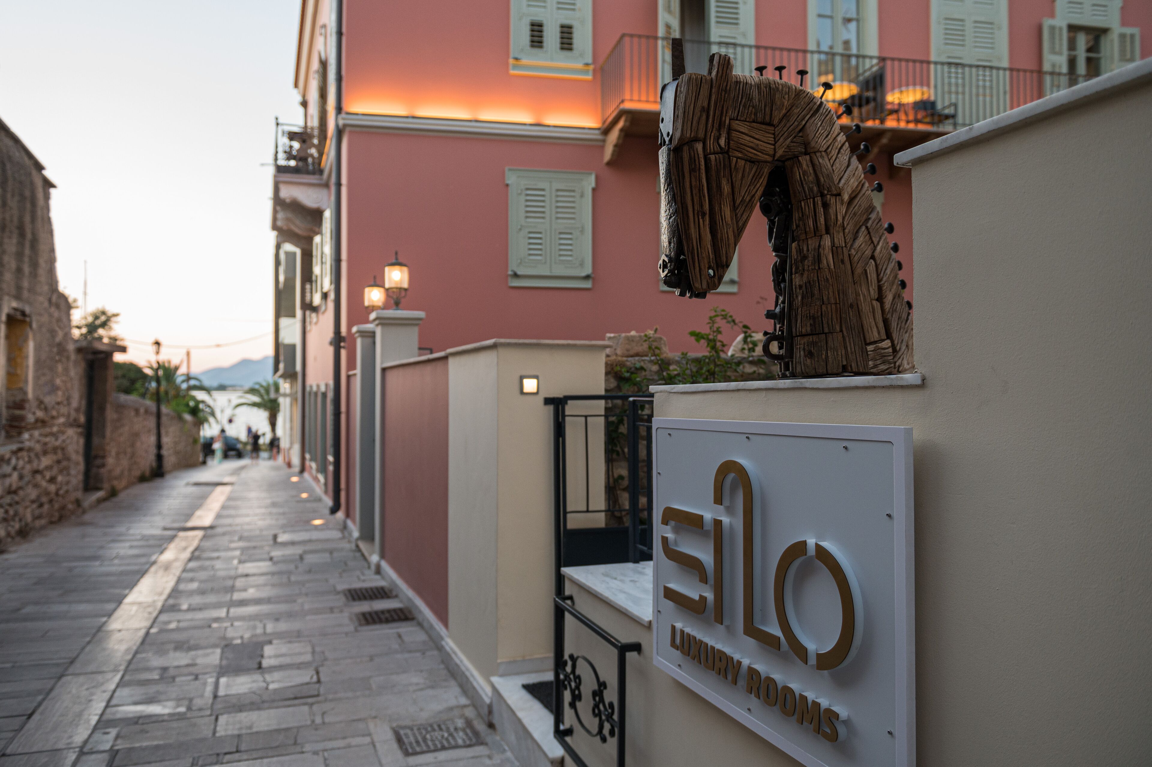 A narrow street with a building labeled "ELLO LUXURY ROOMS".