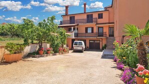 A two-story house with a driveway leading to a white van parked in front. - Holiday apartment with air conditioning (Medulin)