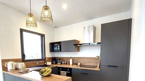 Una cocina moderna con una isla central, armarios oscuros e iluminación colgante.