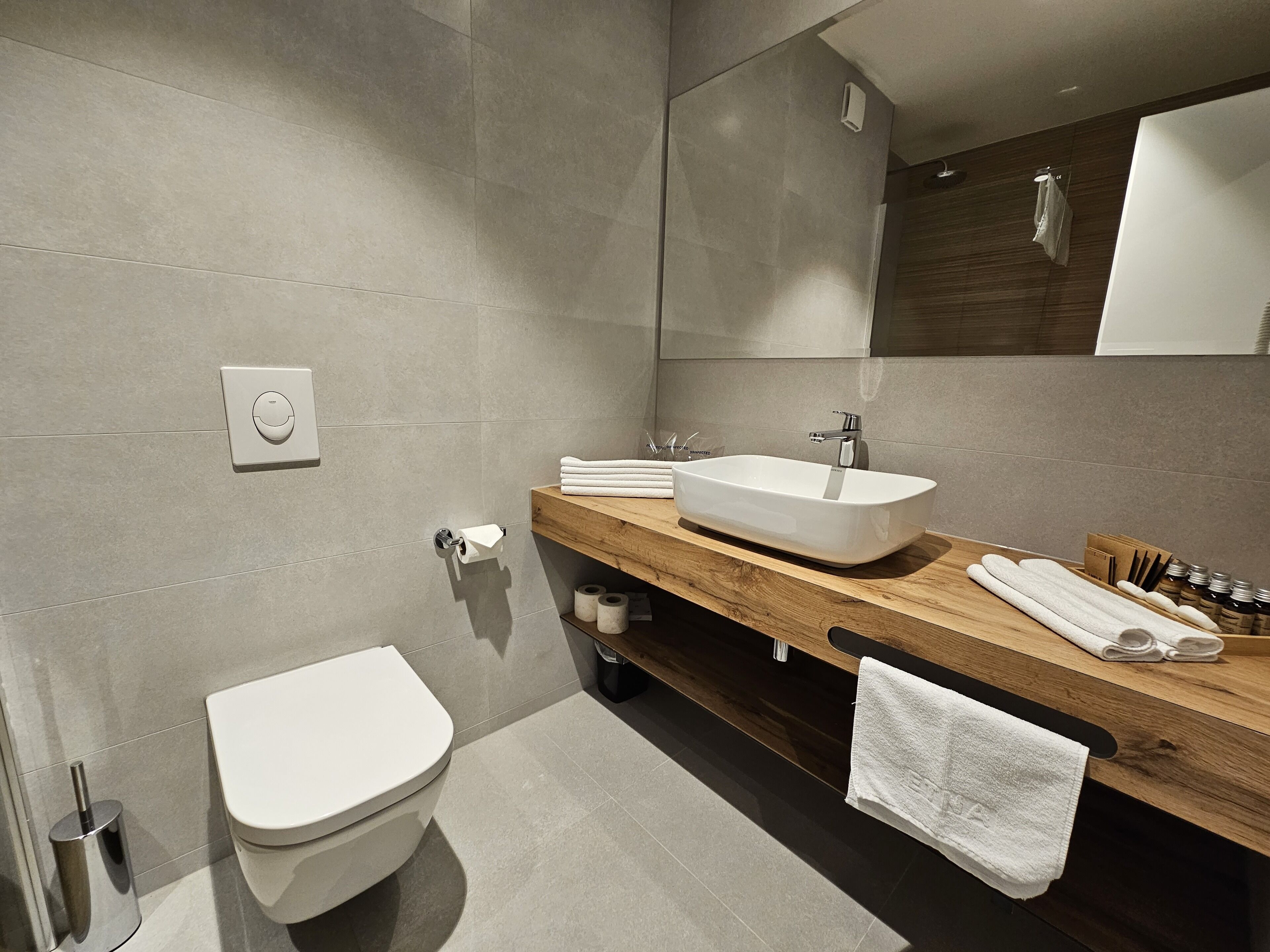 A modern bathroom with a toilet, sink, and mirror.