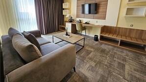 Ein modernes Wohnzimmer mit einer Couch, einem Couchtisch und einem an der Wand befestigten Fernseher.