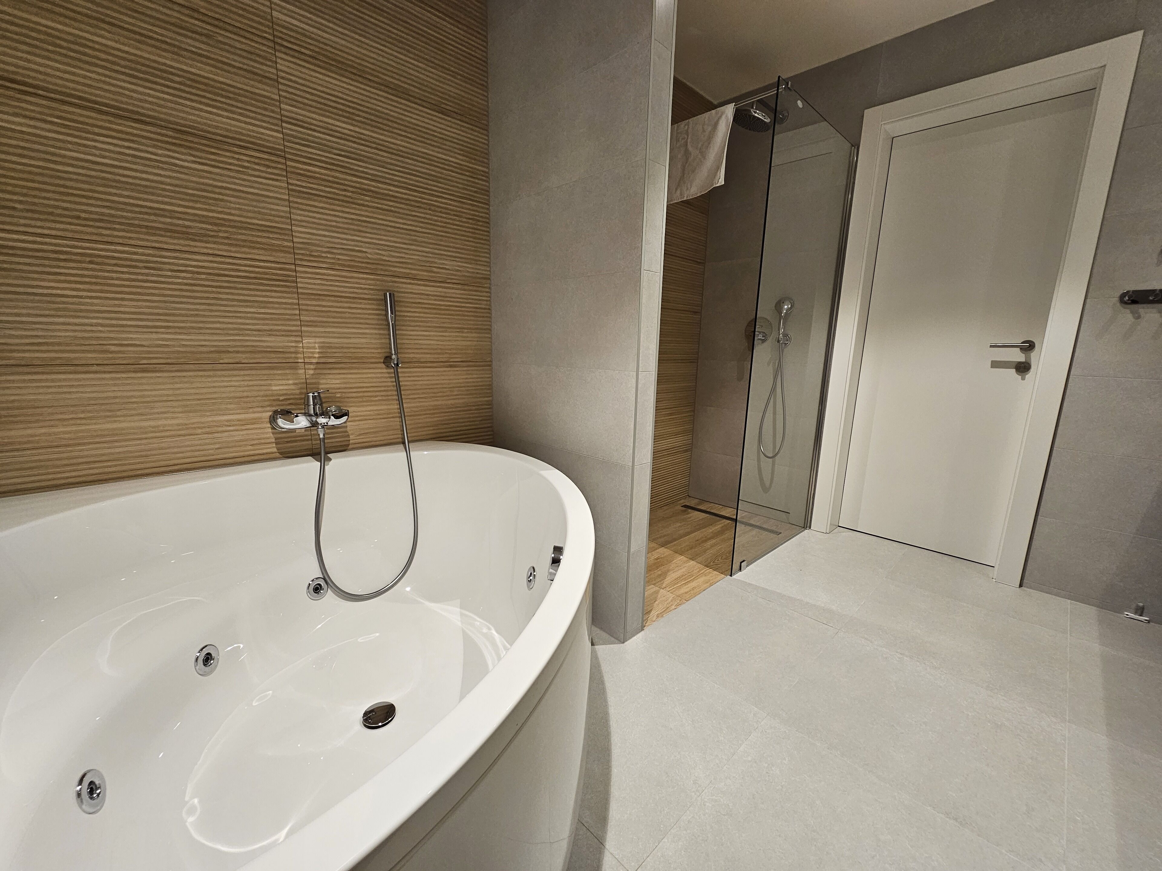 A modern bathroom with a freestanding bathtub, a glass-enclosed shower, and a wooden panel wall.