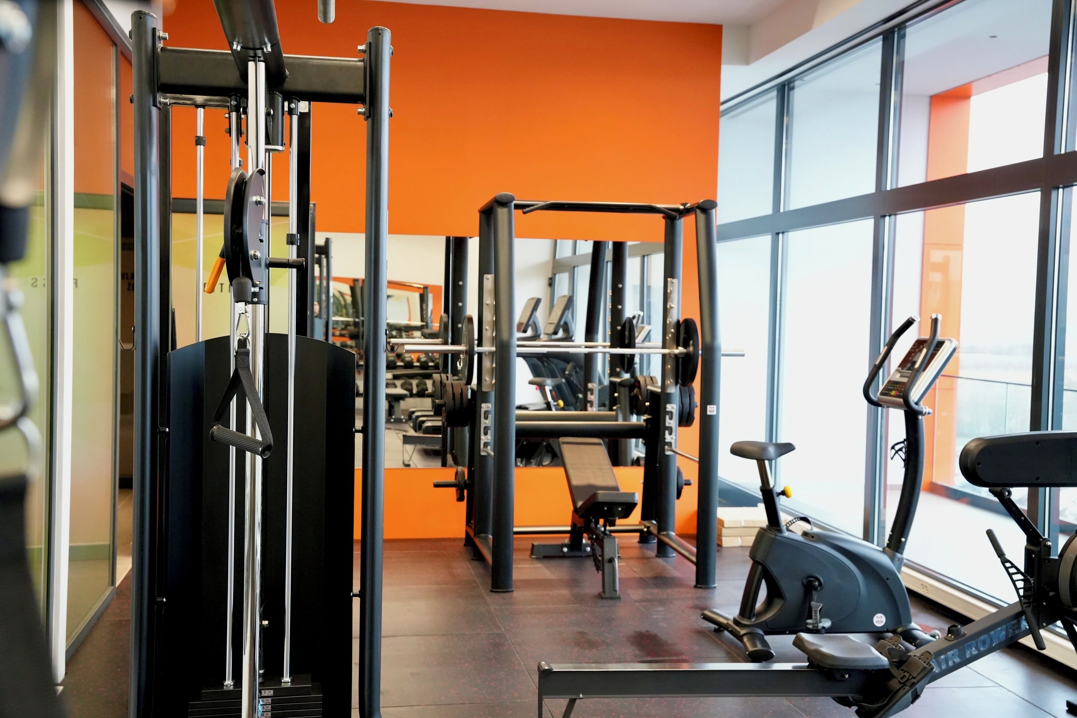 A gym with exercise equipment, a treadmill, and large windows.