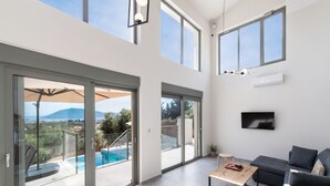 Un vaste espace de vie avec vue sur la piscine, un téléviseur à écran plat et un canapé moderne.