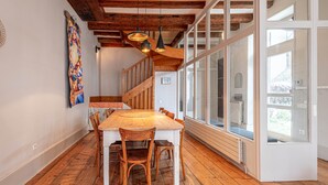 A dining area with a wooden table and chairs, a staircase, and large windows. - Venez Chez Vous La Maison des Balmettes (Annecy)