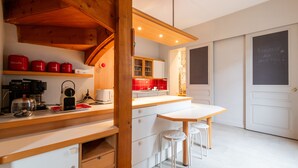 A modern kitchen with wooden beams, a white countertop, and red storage containers. - Venez Chez Vous La Maison des Balmettes (Annecy)
