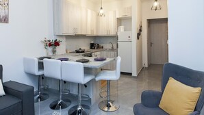 A modern kitchen with white cabinets, a marble countertop, and a central island with bar stools. - Ano Kipseli Athens Gem 1 Bd Apt for 4 (Athens)