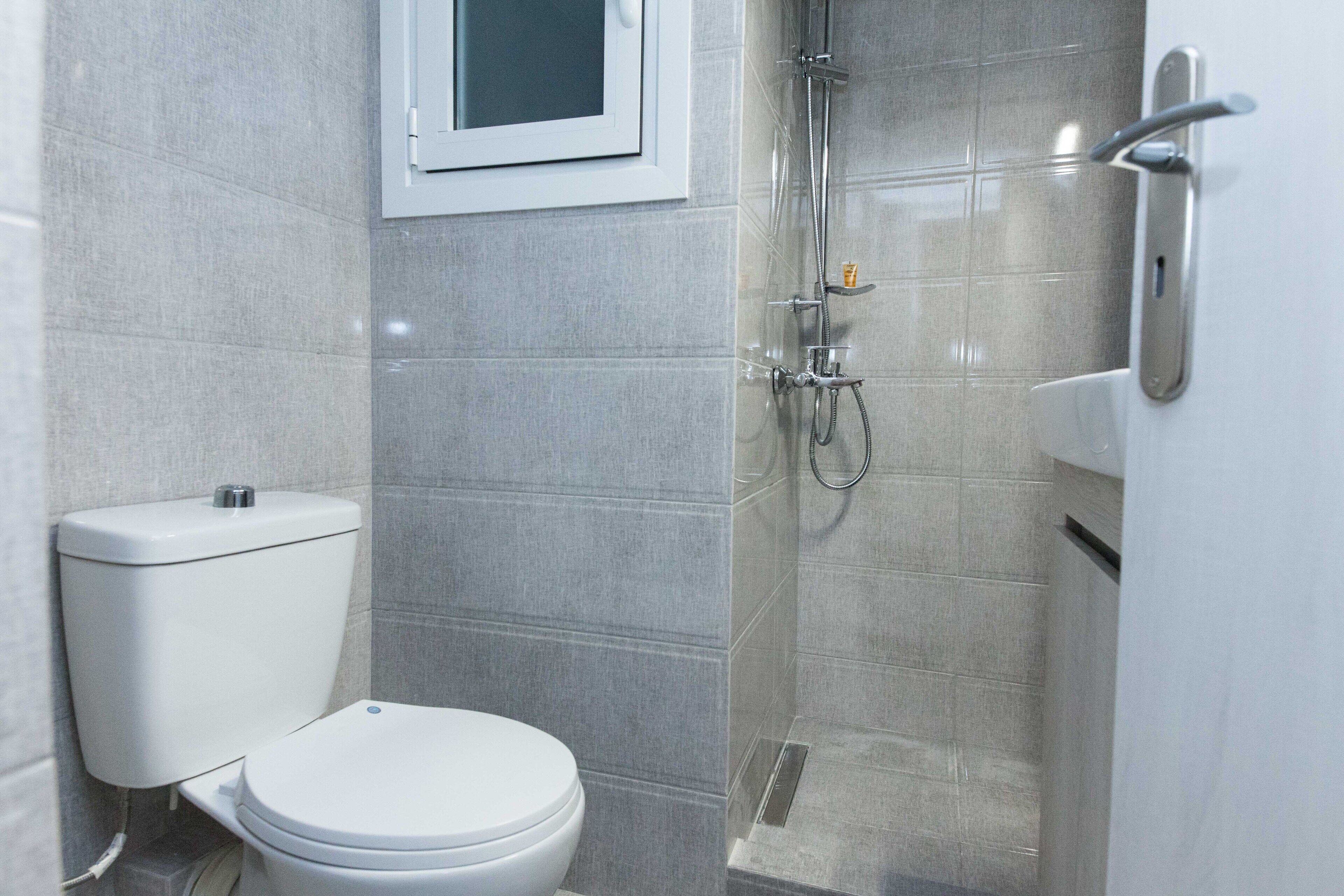 A bathroom with a toilet, a shower, and a sink.