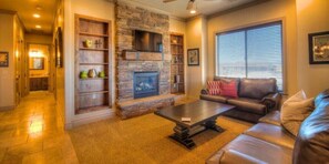 A cozy living room with a stone fireplace, a leather sofa, and a coffee table.