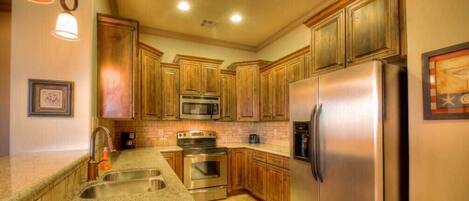 A kitchen with wooden cabinets, stainless steel appliances, and a granite countertop.