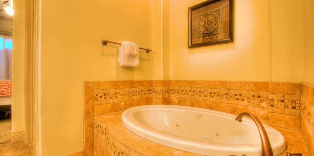 A bathroom with a large bathtub, a towel rack with a towel, and a framed picture on the wall.